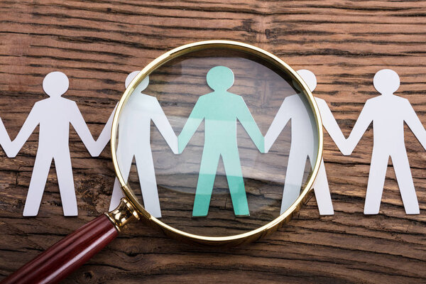 Высокий вид на увеличивающееся стекло на вырезанных фигурах на вуденовском столе
