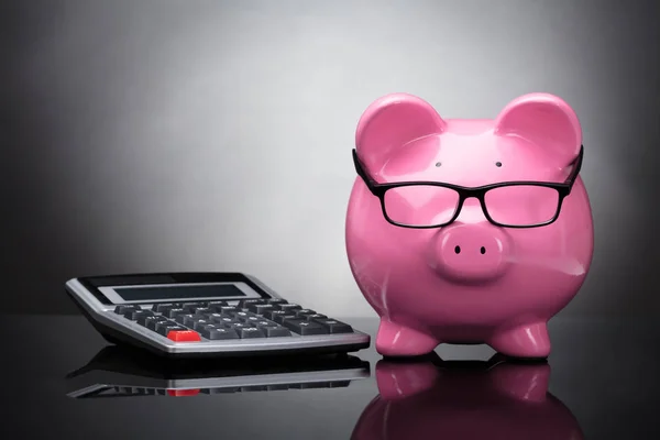 Крупный План Pink Piggy Bank Калькулятора Сером Фоне — стоковое фото