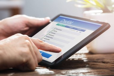 Dijital tablet denetim listesi formu doldururken bir işadamının'ın el Close-Up