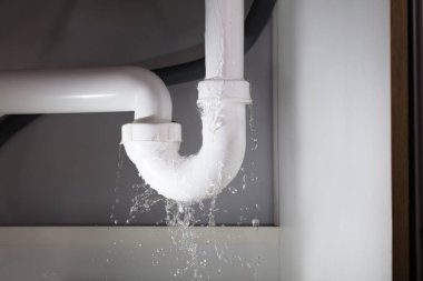 Beyaz lavabo borusundan su sızıyor.