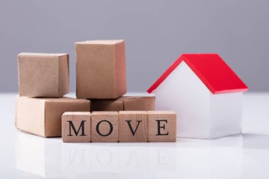 Karton kutular ve ev modeli önünde tahta bloklar hareket metni