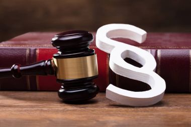 Büyük beyaz paragraf sembolü, çekiç ve hukuk kitabını ahşap masa üzerinde yakın çekim