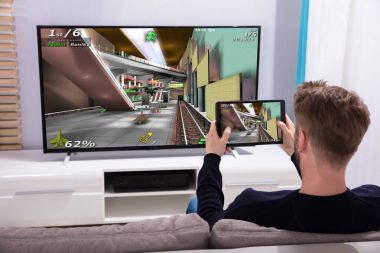 Arkadan görünüş genç bir adamın oyunu televizyonda Wi-fi dijital tablet aracılığıyla bağlanma
