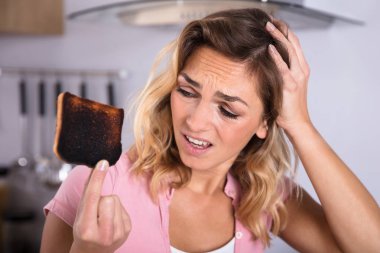 Sinir bozucu genç kadın Holding Close-Up yanmış tost mutfak
