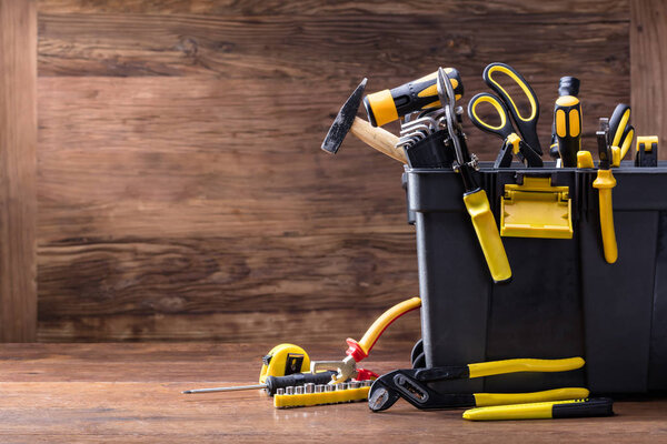Plastic Black Container With Many Tools On Wooden Desk