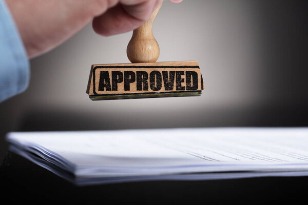 Close-up Of A Businessperson's Hand Stamping On Approved Contract Form