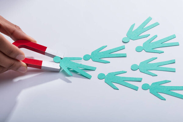 Крупный план руки бизнесмена, держащего на столе магнит "Красная подкова"
