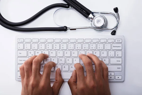 Médico Digitando Teclado Computador Com Estetoscópio Mesa Branca — Fotografia de Stock