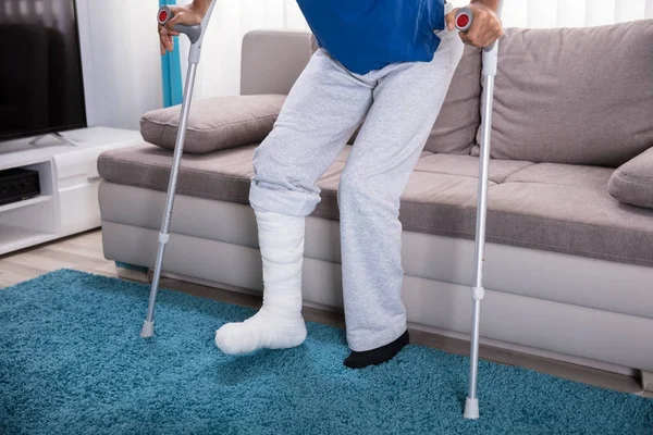 Hombre Con Pierna Rota Usando Muletas Para Caminar Sobre Alfombra —  Fotos de Stock