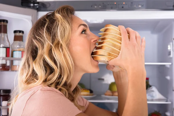 Närbild Hungrig Kvinna Äter Smörgås Nära Kylskåp — Stockfoto