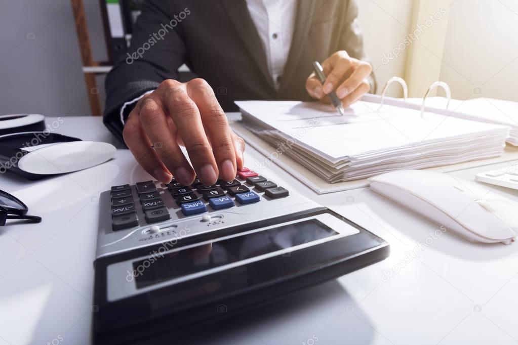 Close-up Of A Businessperson's Hand Calculating Bill With Calculator