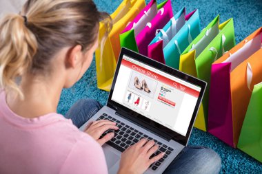 Close-Up halı üzerinde renkli alışveriş torbaları ile dizüstü bilgisayar kullanma Online alışveriş kadın