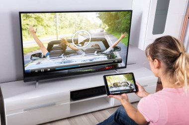 Oturma odasında televizyon izlerken dijital Tablet kullanan genç kadın
