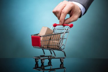 Alışveriş sepeti gri arka plan üzerine karton kutular ile tutan işadamı'nın el