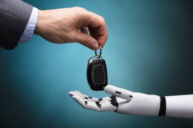 Robot gri arka plan üzerinde araba anahtarı veren bir işadamının'ın el Close-Up
