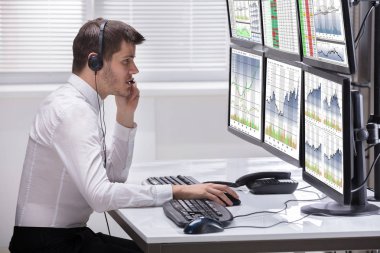 Grafikler birden çok bilgisayar ekranlarında analiz bir genç erkek borsa Broker yan görünüm