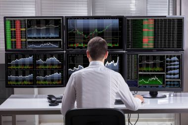 Side View Of A Young Male Stock Market Broker Analyzing Graphs On Multiple Computer Screens clipart