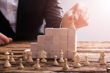 Bir işadamının'ın el satranç parça ahşap bloklar üzerinde düzenleme Close-Up