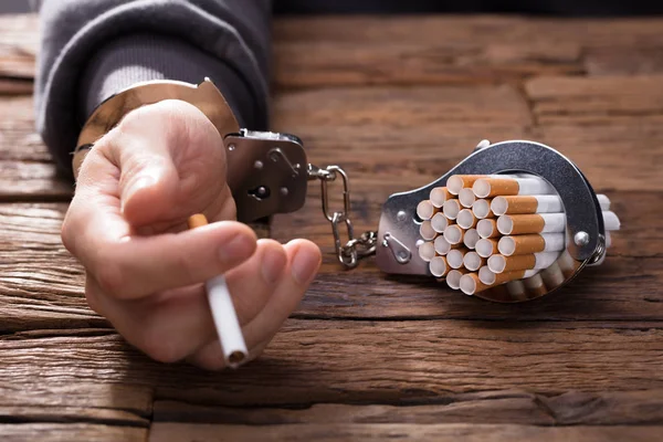 Närbild Persons Hand Med Handfängsel Och Cigaretter Trä Skrivbord — Stockfoto