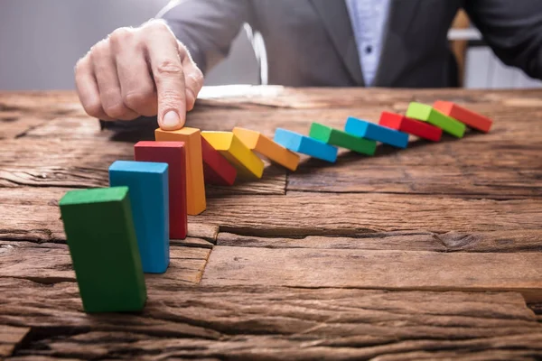 Close Businessperson Stopping Colorful Falling Dominos Finger Wooden Desk — Stock Photo, Image