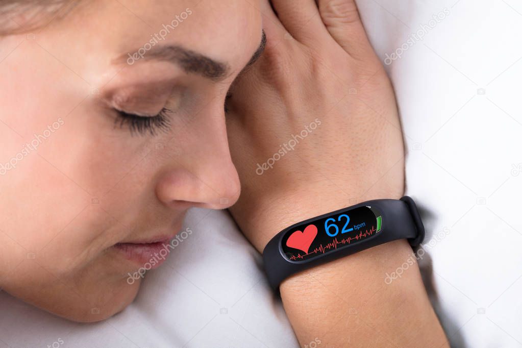 Fitness Activity Tracker With Heartbeat Rate On Woman Hand Over Bed