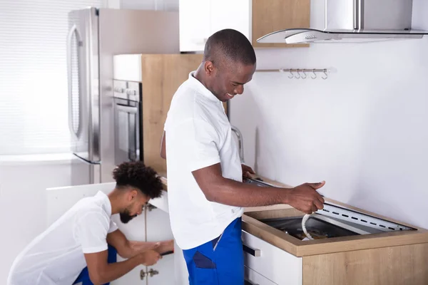 Two Young Handy Men Uniform Fixing Induction Stove Sink Pipe — Stock Photo, Image