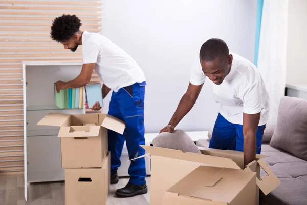 Two Young Movers Placing Books Shelf Cardboard Boxes — Stock Photo, Image