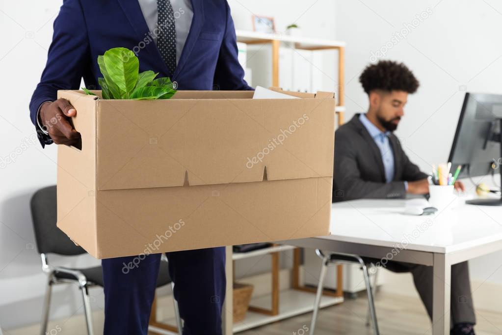 Close-up Of A Businessperson's Hand Holding Belongings In Cardboard Box