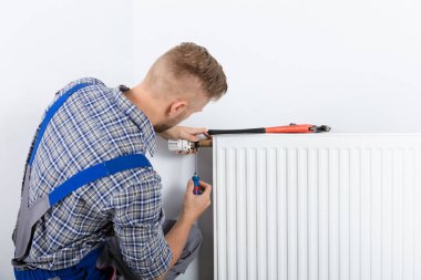 Arkadan görünüş erkek tesisatçı termostat tornavida ve İngiliz anahtarı radyatör sabitleme