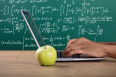 Yakın çekim yeşil elma yakınındaki Laptop sınıfta kullanarak el