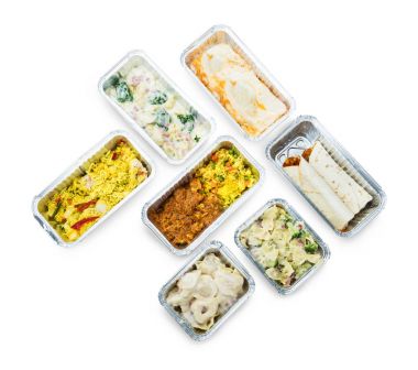 Beyaz arka plan üzerinde folyo kaplarda lezzetli yiyeceklerin yüksek açılı görünüş