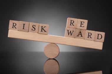 Risk ve ödül arasında dengesizlik gri arka plan üzerinde gösterilen bir ahşap tahterevalli Close-Up