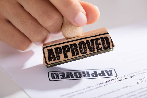 Close-up Of Person's Hand Approving Contract Form