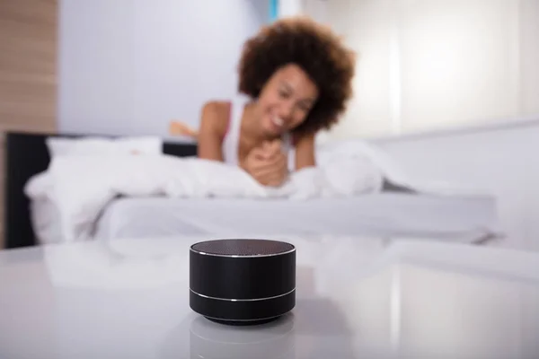 Smiling Young Woman Lying Bed Listening Music Wireless Speaker — Stok Foto