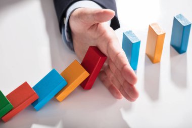 Masanın üzerine düşmesini renkli Domino durdurma bir işadamının yüksek açılı görünüş