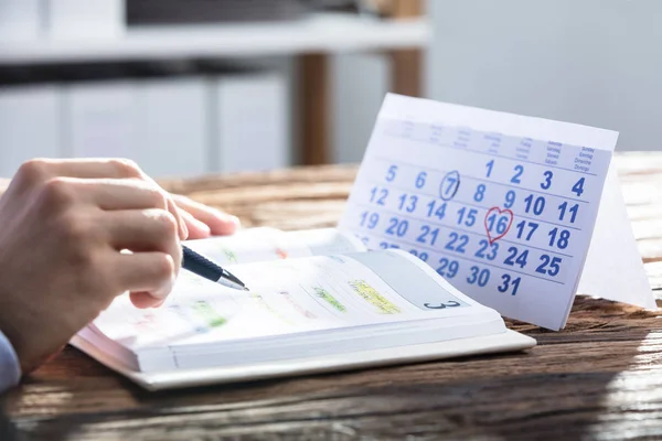 Horario Mano Del Empresario Que Comprueba Diario Con Calendario Escritorio — Foto de Stock