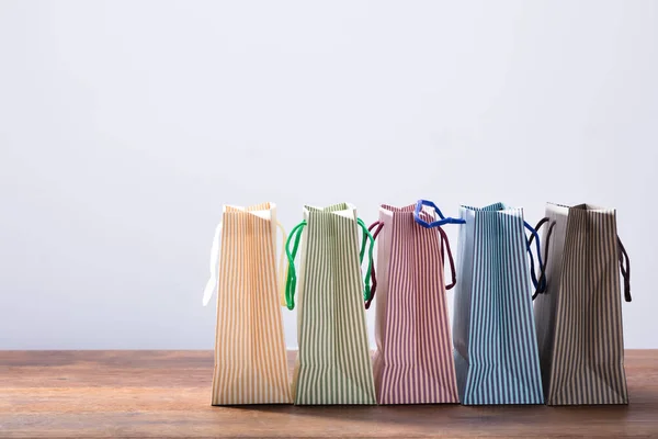 Row Colorful Stripped Shopping Bags Wooden Table White Background — Stock Photo, Image