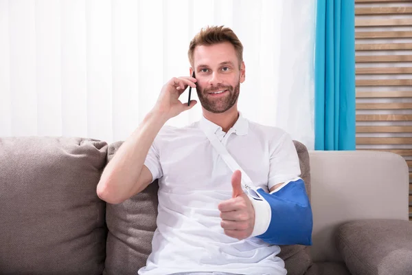 Man Fractured Hand Gesturing Thumbs While Talking Mobile Phone — Stock Photo, Image