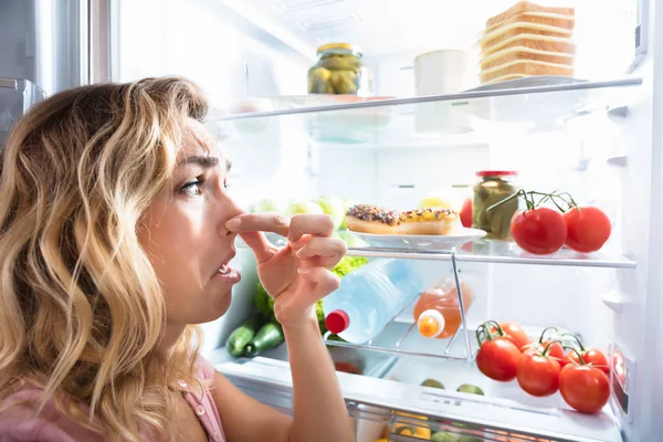 Крупный План Молодой Женщины Держащей Нос Рядом Грязной Едой Холодильнике — стоковое фото