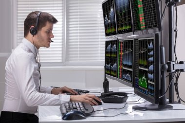 Grafikler birden çok bilgisayar ekranlarında analiz bir genç erkek borsa Broker yan görünüm