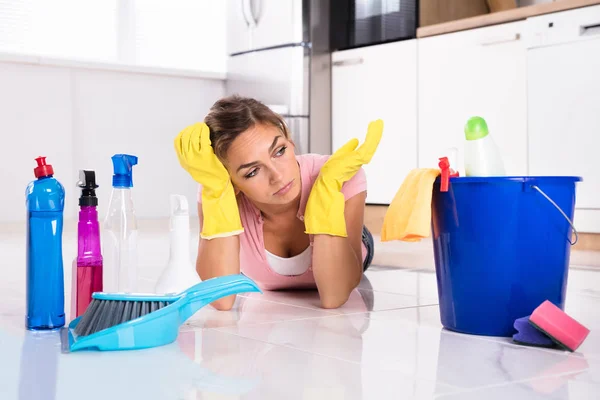 Triste Joven Mujer Acostada Piso Cocina Mirando Productos Equipos Limpieza — Foto de Stock