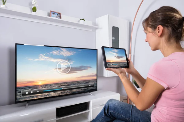 リビング ルームでテレビを見るデジタル タブレットを使用して若い女性 — ストック写真