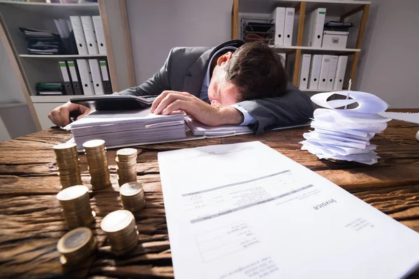 Geschäftsmann Schläft Büro Mit Rechnung Und Gestapelten Goldmünzen Auf Holztisch — Stockfoto