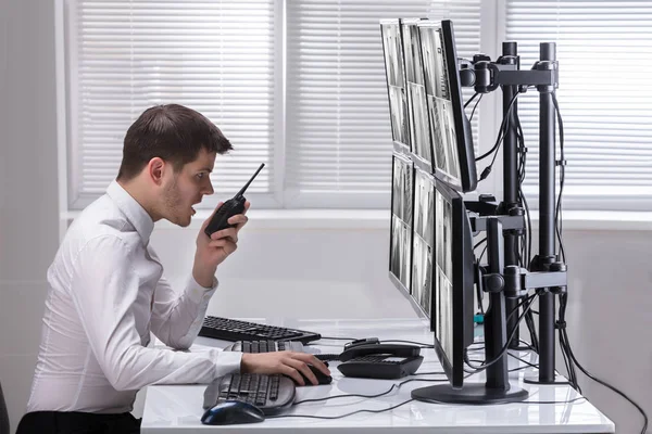 Young Male Security Guard Talking Walkie Talkie While Monitoring Multiple — Stock Photo, Image