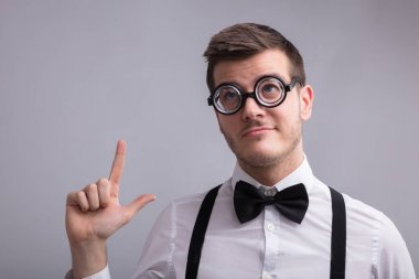 Genç gri arka plan üzerinde işaret gözlük takan adam