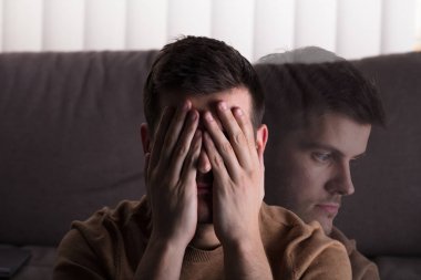 Kanepe önünde evde oturan genç üzgün adam