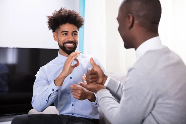 Två Unga Lyckliga Män Sitter Soffan Att Göra Teckenspråk — Stockfoto