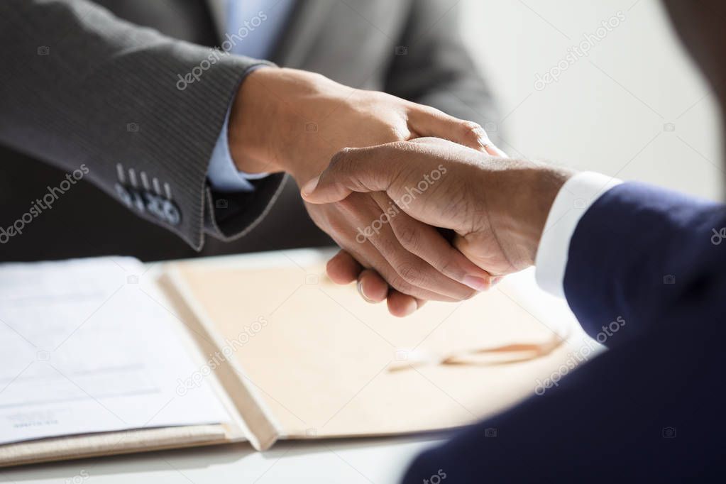 Close-up Of Businessperson Shaking Hand With Candidate At Workplace