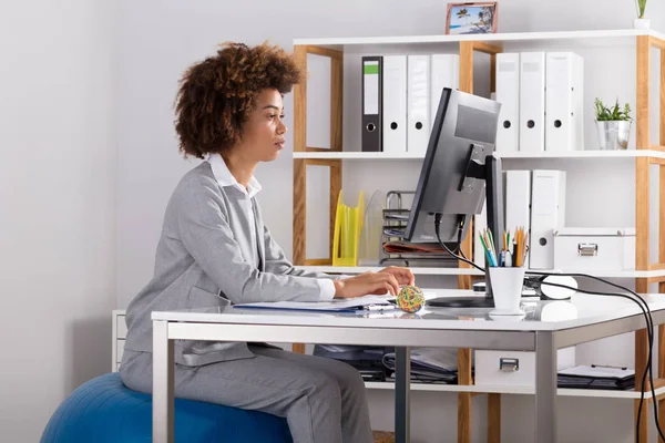 Junge Geschäftsfrau Benutzt Computer Während Sie Büro Auf Fitnessball Sitzt — Stockfoto