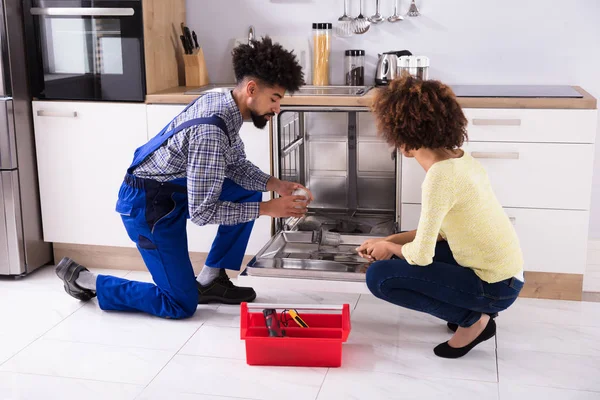 Jovem Mulher Olhando Para Masculino Reparador Fixando Máquina Lavar Louça — Fotografia de Stock